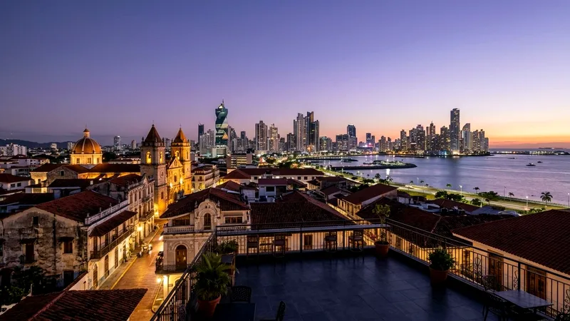 Colonial rooftops of Casco Viejo with Panama City's modern skyline beyond at dusk.